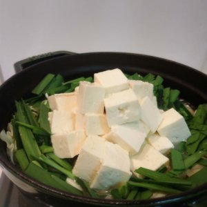 調理中のもつ鍋に野菜を入れた写真